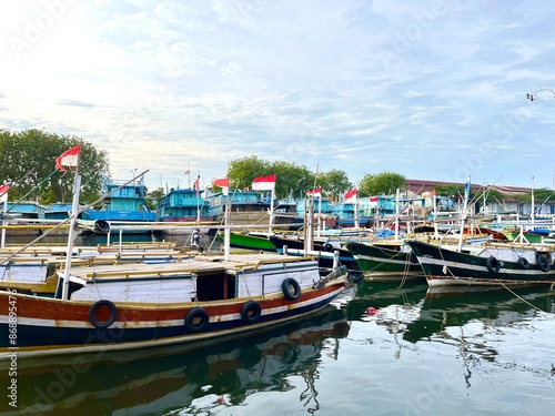 Several traditional wooden fishing and passengers boats with Indonesian Flag moored in Probolinggo fishing port photo