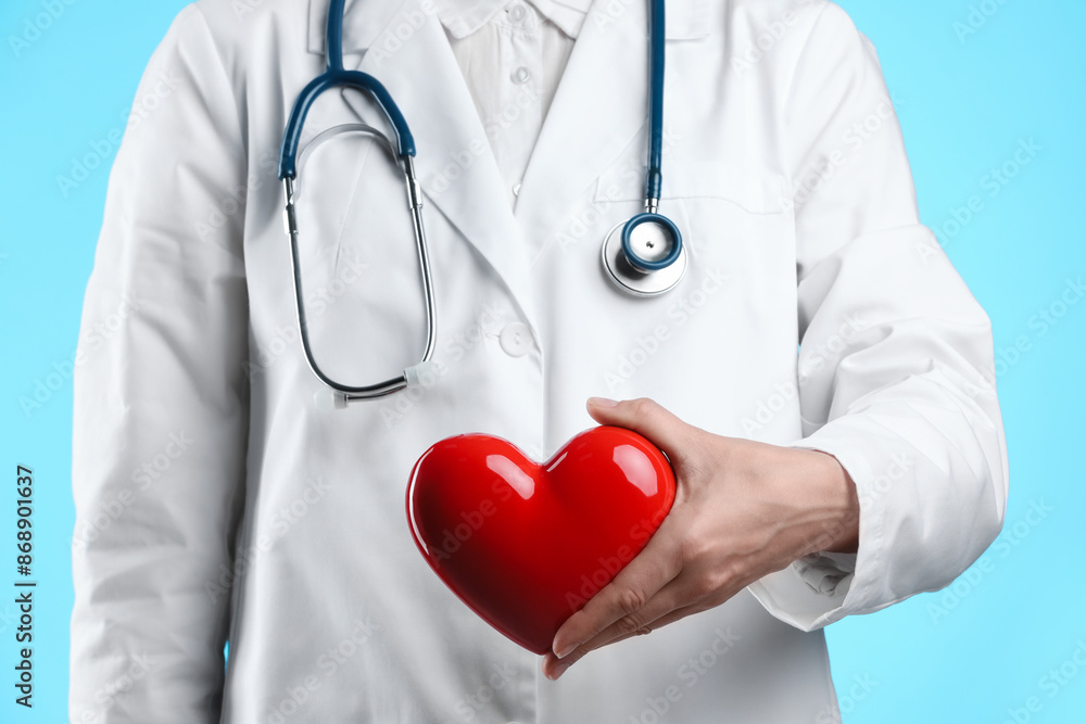 Doctor with red heart on light blue background, closeup Doctor with red heart on light blue background, closeup