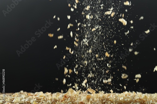 Dry natural sawdust falling on black background photo