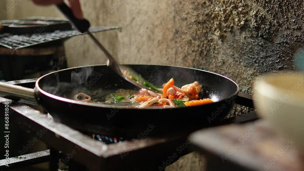 The chef is cooking Seafood spaghetti in a hot pan in the restaurant's kitchen. The chef is cooking Seafood spaghetti in a hot pan in the restaurant's kitchen.