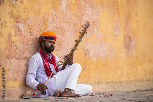 Picture of a Rajasthani artist playing violin on street. Jaipur, Pushkar, Jodhpur, Jaisalmer, desert, forts, sight seeing, tourism, attractive, music, tune, fine, string, wind, stick, wood, practice.
