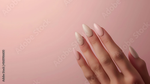 A woman hand with an almond shaped nails, painted in a French manicure style against a plain pink background. photo