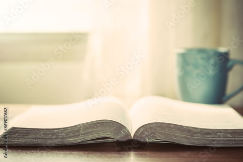 close up of open bible with a cup of coffee for morning devotion on wooden table with window light, christian background

