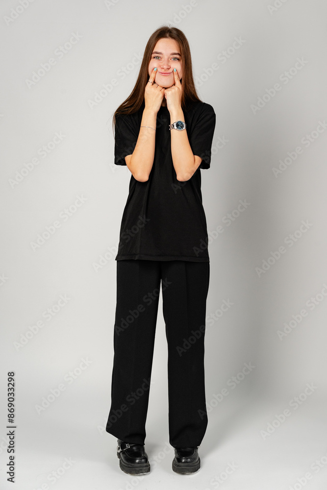 Young Woman Smiling With Hands on Cheeks Against a Gray Background