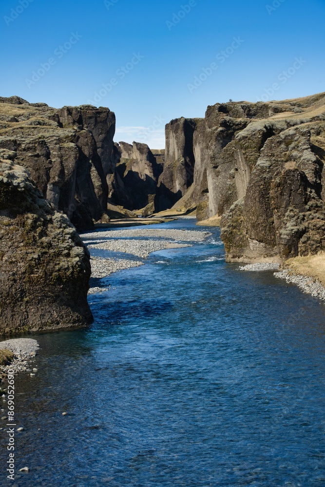 View of Fjadrargljufur Canyon in Iceland with clear blue skies and a flowing river View of Fjadrargljufur Canyon in Iceland with clear blue skies and a flowing river