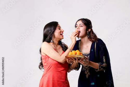 Two Beautiful Women Wearing Traditional Clothes Feeding Ladoo To Her Friend