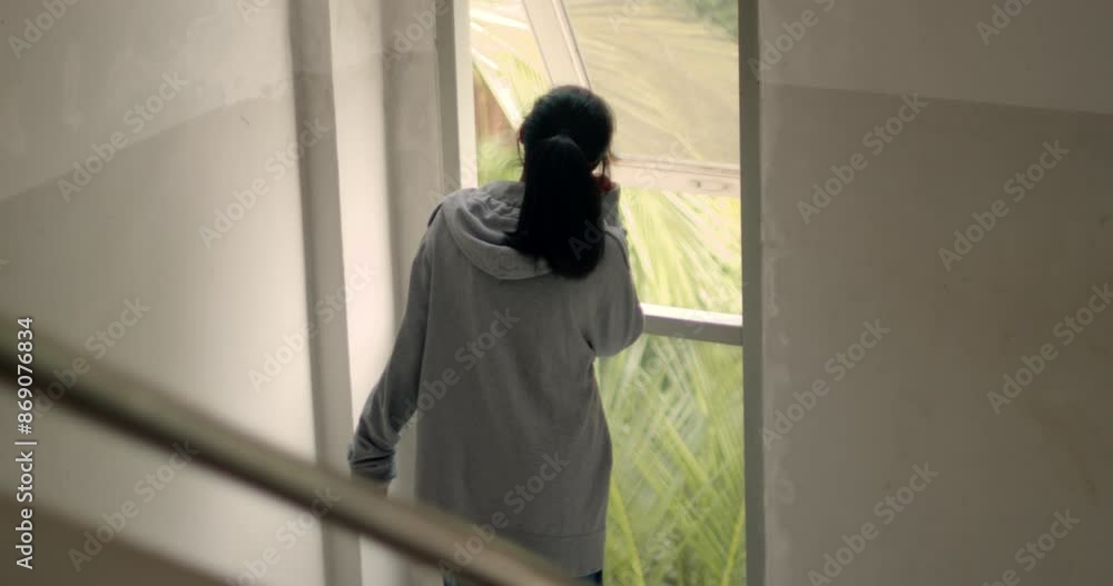 An Asian female high school student was joyfully dancing to music through Bluetooth earphones on her phone while standing by the window after school, secretly reveling in her happy mood. An Asian female high school student was joyfully dancing to music through Bluetooth earphones on her phone while standing by the window after school, secretly reveling in her happy mood.