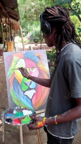 Young african man listening to music while painting outdoors