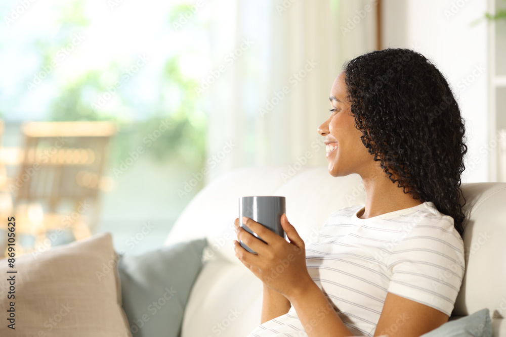 Happy black woman drinking and looking through a window Happy black woman drinking and looking through a window