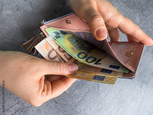 woman puts 50 100 euros in wallet or caunt money. Saving concept photo