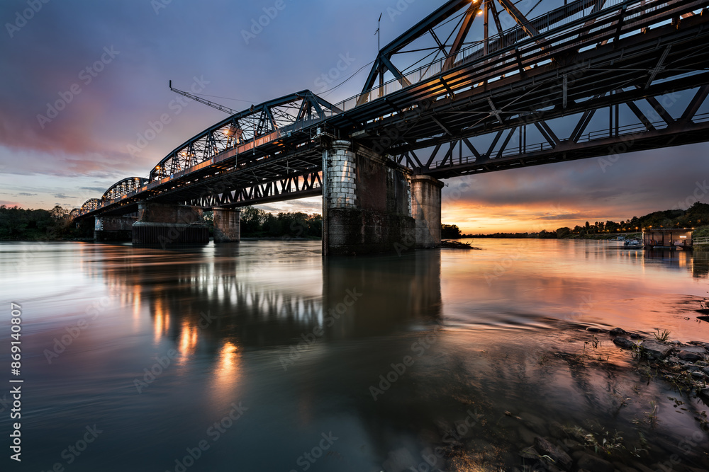 The big bridge of the city and its reflections on the river in the sunset light, Cremona, Italy The big bridge of the city and its reflections on the river in the sunset light, Cremona, Italy