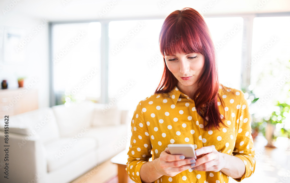 Redhead woman scrolling on smartphone, working from home office. Businesswoman working remotely from her apartment in the city. Redhead woman scrolling on smartphone, working from home office. Businesswoman working remotely from her apartment in the city.