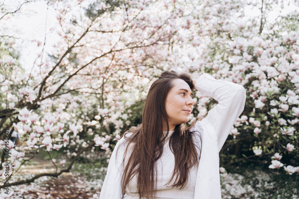 Young woman standing near magnolia flowers tree Young woman standing near magnolia flowers tree