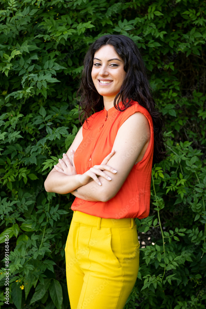 Smiling fashionable woman with arms crossed standing at garden