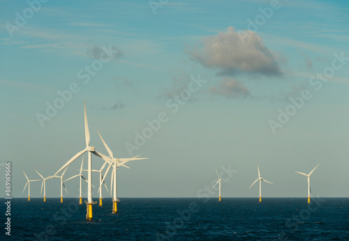 Scattered wind turbines in sea under sky on sunny day photo