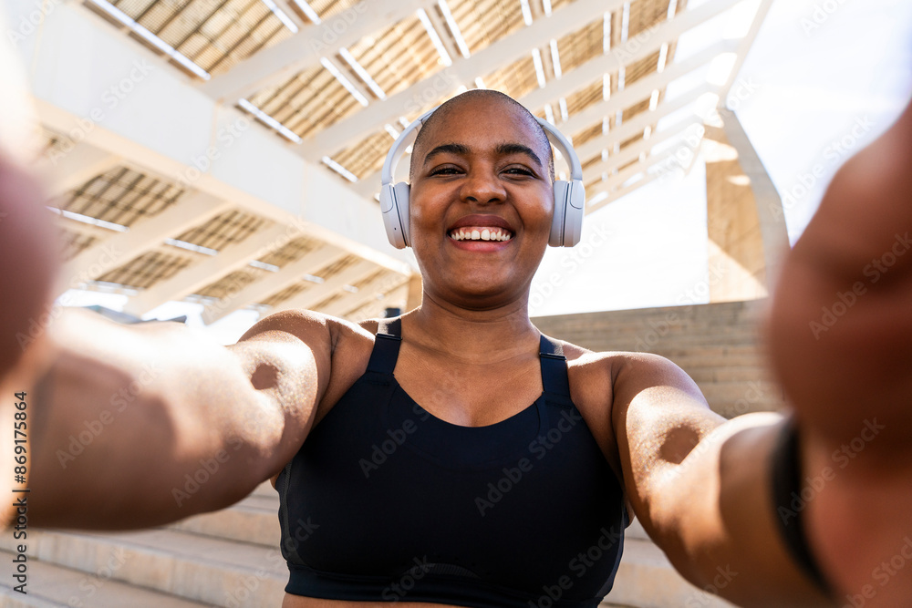 © Westend61 - Happy sporty woman wearing headphones taking selfie on sunny day © Westend61 - Happy sporty woman wearing headphones taking selfie on sunny day