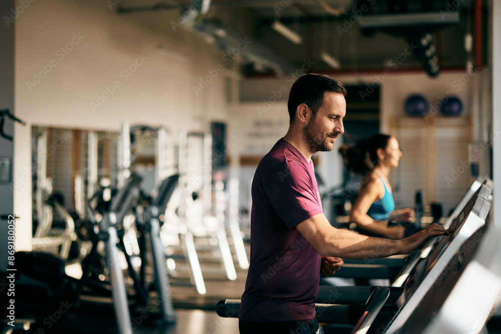A man at the gym, running on a treadmill, female in the background. A man at the gym, running on a treadmill, female in the background.