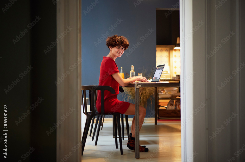 Smiling young woman sitting with laptop near table at home Smiling young woman sitting with laptop near table at home