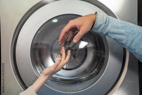 Hands of couple reaching for each other in laundromat photo