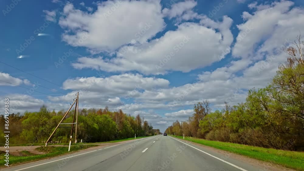 A peaceful dashcam video capturing a drive through a scenic country road under a bright blue sky with fluffy white clouds. A peaceful dashcam video capturing a drive through a scenic country road under a bright blue sky with fluffy white clouds.