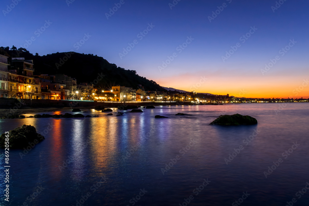 evening or night landscape of evening town coastline in golden lights and sea gulf with calm water and nice reflections with beautisul sunset sky on background evening or night landscape of evening town coastline in golden lights and sea gulf with calm water and nice reflections with beautisul sunset sky on background
