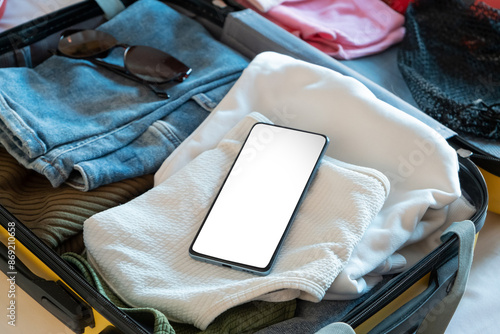 opened packed suitcase on bed in hotel room, mobile phone screem mockup photo