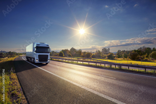 Large Transportation Truck on a highway road through the countryside at sunset