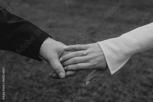 close up of the hands of bride and groom holding each other, showing the engagement ring in black and white