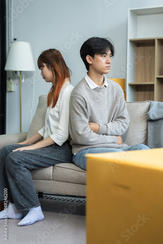 Unhappy young couple sitting apart, having problems in relationship, thinking of breaking up or divorce, upset, family lovers, man and woman avoid talking in relationship problems.