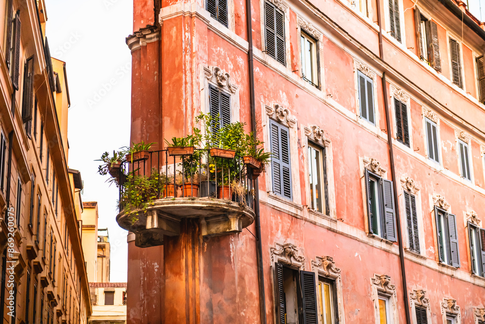 Old architecture in Rome. Italy. Beautiful balcony with flowers on the facade of the house.