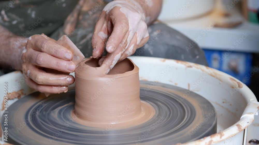 Hand shaping clay pottery with a tools at throwing wheel. Hand shaping clay pottery with a tools at throwing wheel.