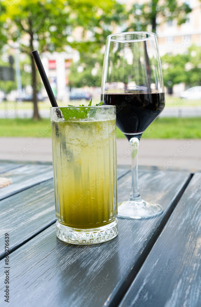 Herbal lemonade and red wine glasses on restaurant table. Family dinner on restaurant summer terrace Herbal lemonade and red wine glasses on restaurant table. Family dinner on restaurant summer terrace