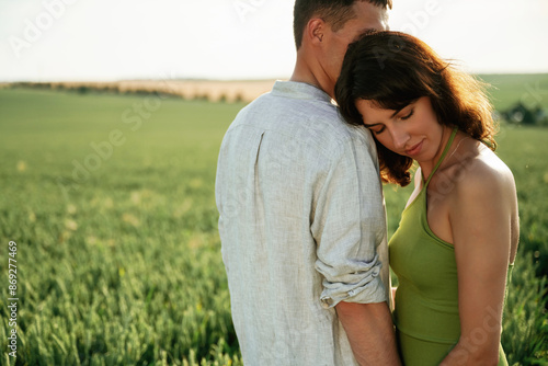 Woman is leaning on man's shoulder. Lovely couple are on the agricultural field together © standret