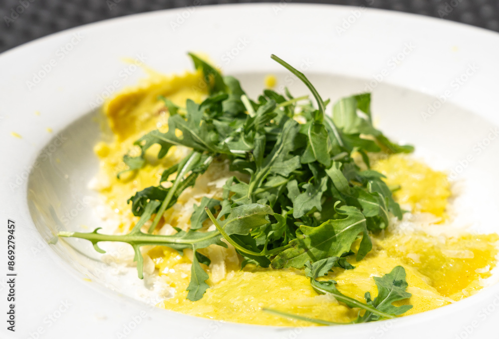 Ravioli, stuffed pasta filled with cheese, arugula topped, grated cheese, served in a lemon zest sauce Ravioli, stuffed pasta filled with cheese, arugula topped, grated cheese, served in a lemon zest sauce