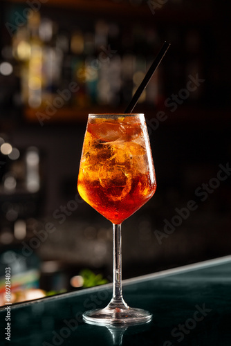 Close up of cold drink in a dark night bar, italian aperol spritz, wine-based cocktail, consists of Prosecco wine, digestive bitters, soda water and oranges.