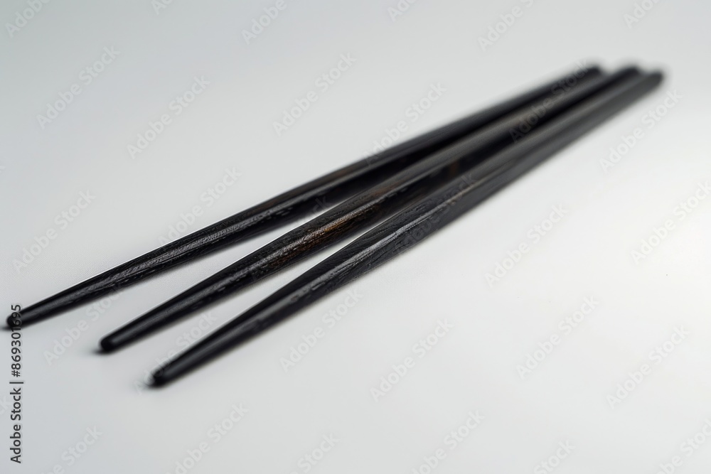 A pair of traditional Asian-style chopsticks placed on a tabletop, ready for use A pair of traditional Asian-style chopsticks placed on a tabletop, ready for use