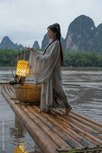 Hanfu Girl holding a lantern on a bamboo raft, Xingping, China. Vertical