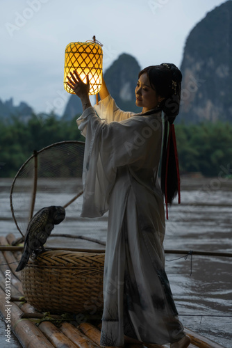 Hanfu Girl holding a lantern on a bamboo raft, Xingping, China. Vertical