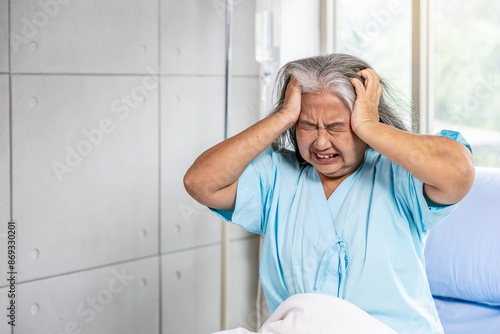 Fotografija Elderly asian woman sitting on bed suffering from headache and migraine so pain