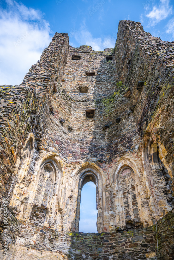 The aged walls and arched windows of Okor Castle stand tall against a bright blue sky, showcasing the architectural remnants near Prague. Czechia The aged walls and arched windows of Okor Castle stand tall against a bright blue sky, showcasing the architectural remnants near Prague. Czechia