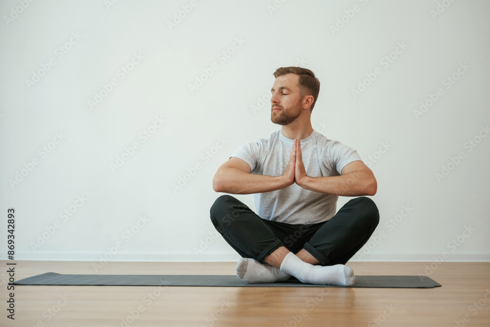 Fototapeta premium Yoga man is sitting on a mat at home
