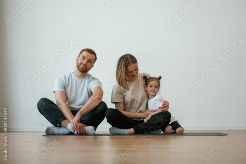 Cheerful people. Family of mother, father and daughter are doing yoga at home