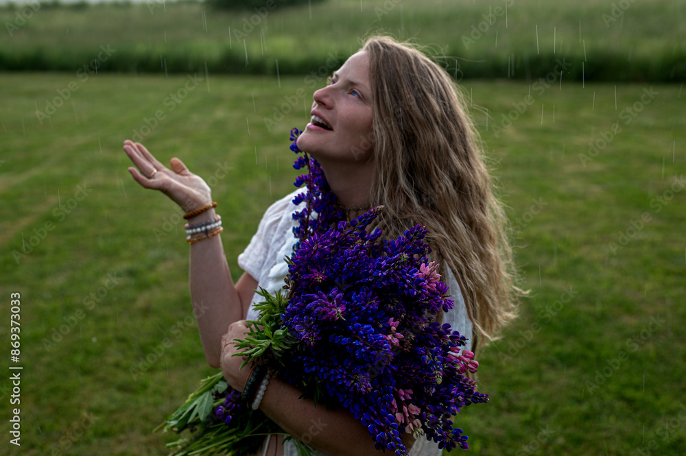 Mature woman holding a bouquet of lupine flowers and standing in the rain