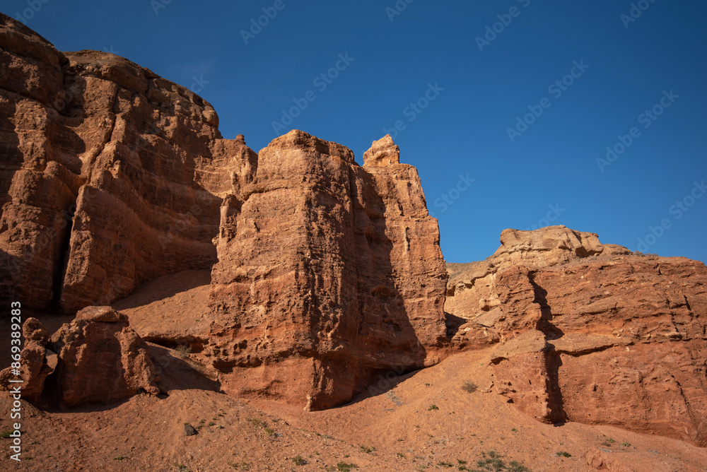 a striking formation of red sandstone cliffs set against a clear azure sky, their rugged textures highlighted by the sunlight, suggesting a peaceful desert scene in daylight a striking formation of red sandstone cliffs set against a clear azure sky, their rugged textures highlighted by the sunlight, suggesting a peaceful desert scene in daylight