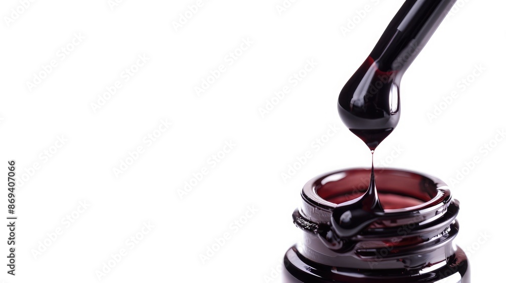 Dropper dripping dark liquid into small brown bottle against white background Dropper dripping dark liquid into small brown bottle against white background