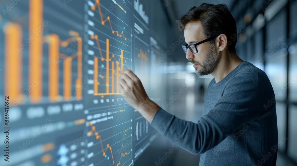 Focused man analyzing data on a futuristic digital screen, representing technology and data analysis in a modern workspace.