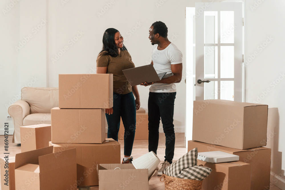 With laptop. African American couple are moving into new house With laptop. African American couple are moving into new house