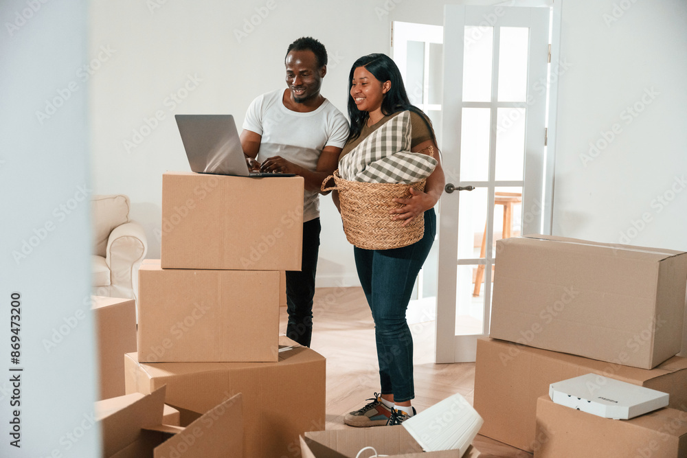 Wireless device, using laptop. African American couple are moving into new house Wireless device, using laptop. African American couple are moving into new house