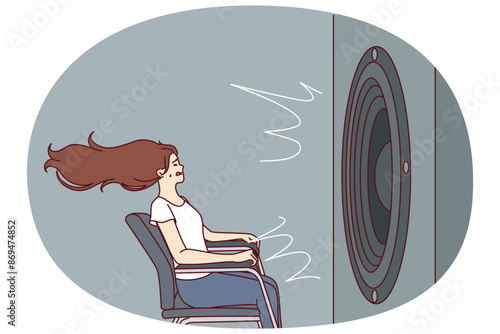 Deafened woman near giant subwoofer from music center listening to loud rhythmic track with bass sitting in chair. Subwoofer with round speaker produces loud sound waves for girl who loves rock songs
