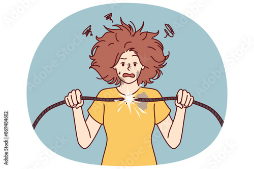 Woman with damaged electrical wire suffers from electric shock and power failure. Funny girl with disheveled hair was shocked after feeling shock from electricity and trying to fix wiring